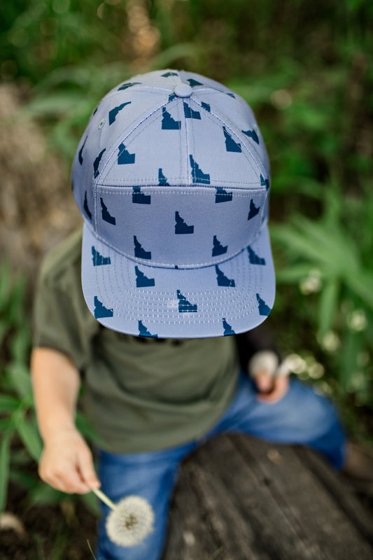 A little boy is wearing an adorable Idaho hat. This Idaho hat fits perfect on those Idaho kids. It has little Idaho's all over it. The hat is designed by TatorJo.