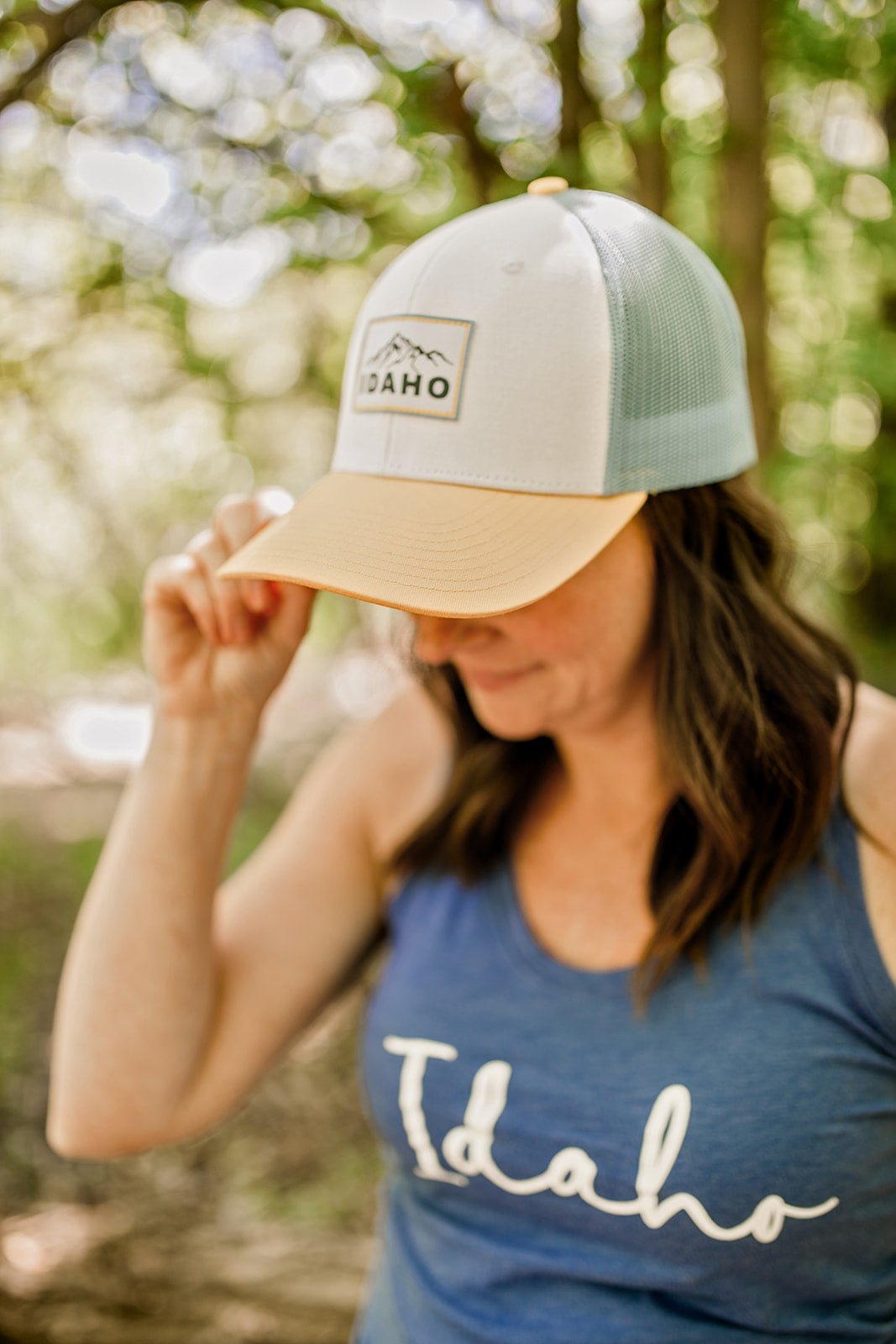 This Idaho racerback is available in blue and gray. It is a triblend tank top that is soft to the touch and ultra soft. It has Idaho designed on it. Idaho apparel is a must! Along with this Idaho hat the women is wearing.
