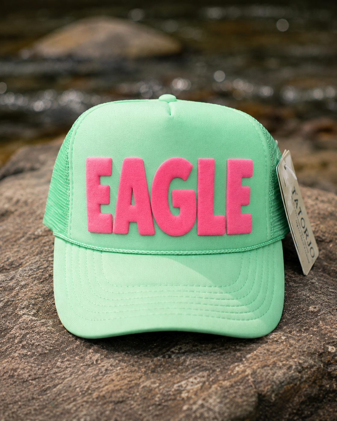 Green cap with pink 'EAGLE' text on a rock surface