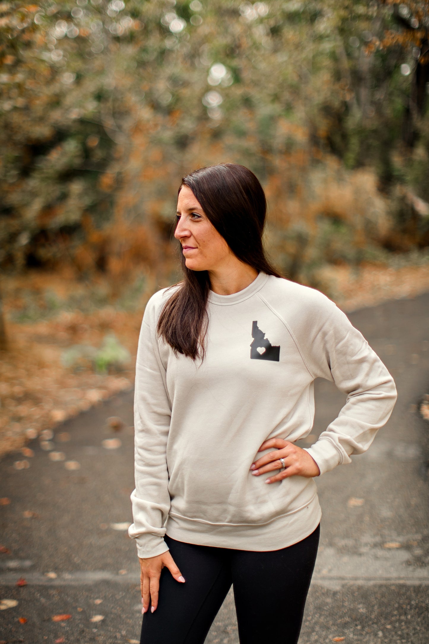 A young mom wearing an Idaho sweater. The Idaho sweater has an Idaho heart on it. This Idaho sweater is designed by TatorJo, and Idaho clothing company.