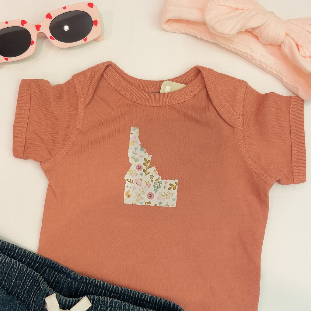 Idaho Onesie with a flower Idaho on the front.