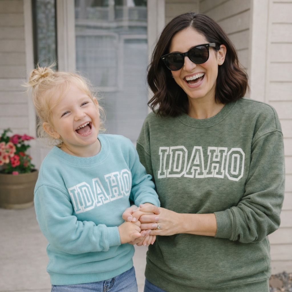 Woman and child wearing Idaho sweatshirts standing outside a house.