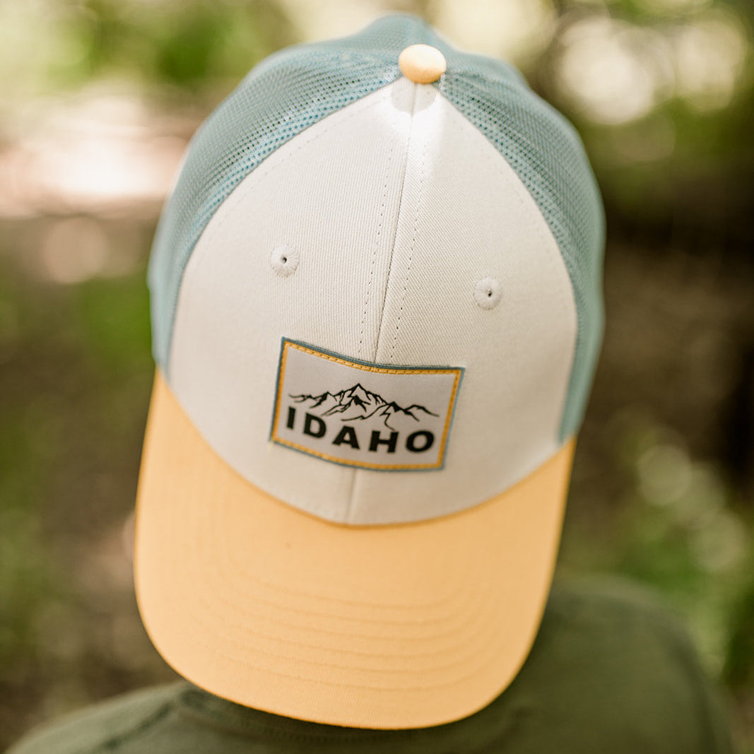 Modern Idaho Trucker Hat on a young Idaho boy. featuring a bold mountain patch and yellow brim—designed by TatorJo, a small Idaho apparel business.