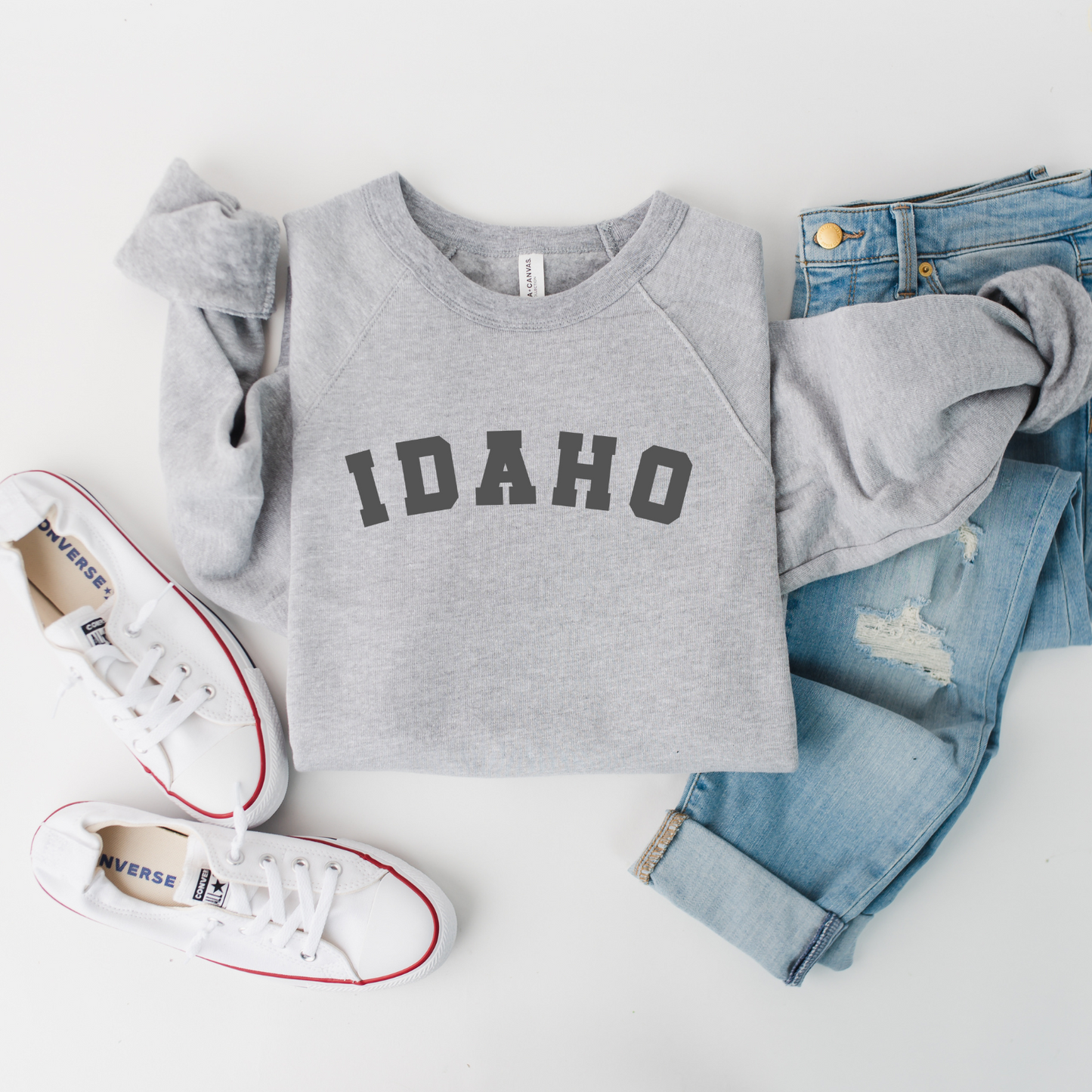 This Idaho sweater has the word Idaho on it. The Idaho is a deep gray and it's printed on a gray sweater. This Idaho sweatshirt is cozy and comfortable. The shirt is designed by TatorJo, an Idaho Clothing Company.