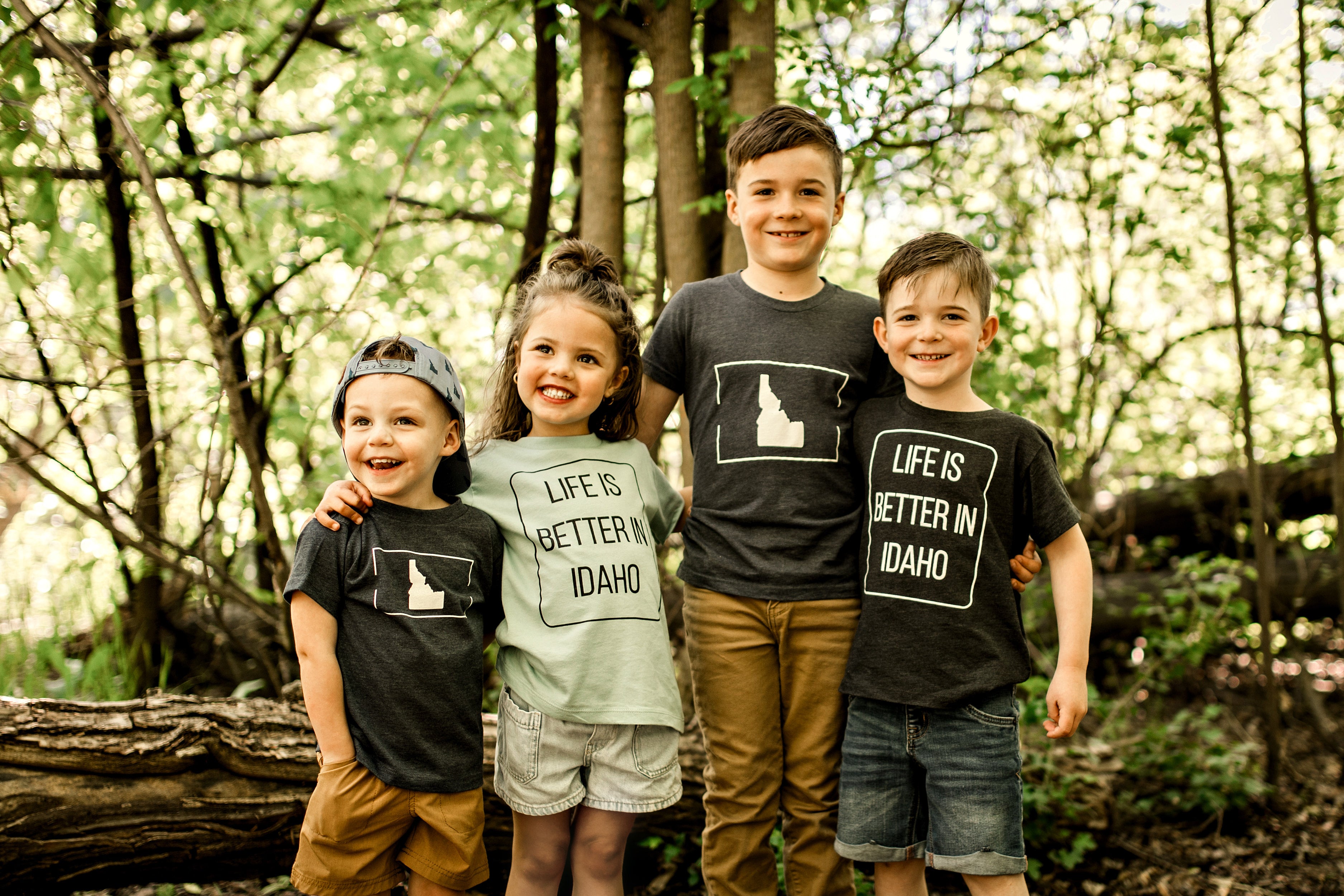 Four children wearing t-shirts with 'Life is Better in Idaho' in a forest setting