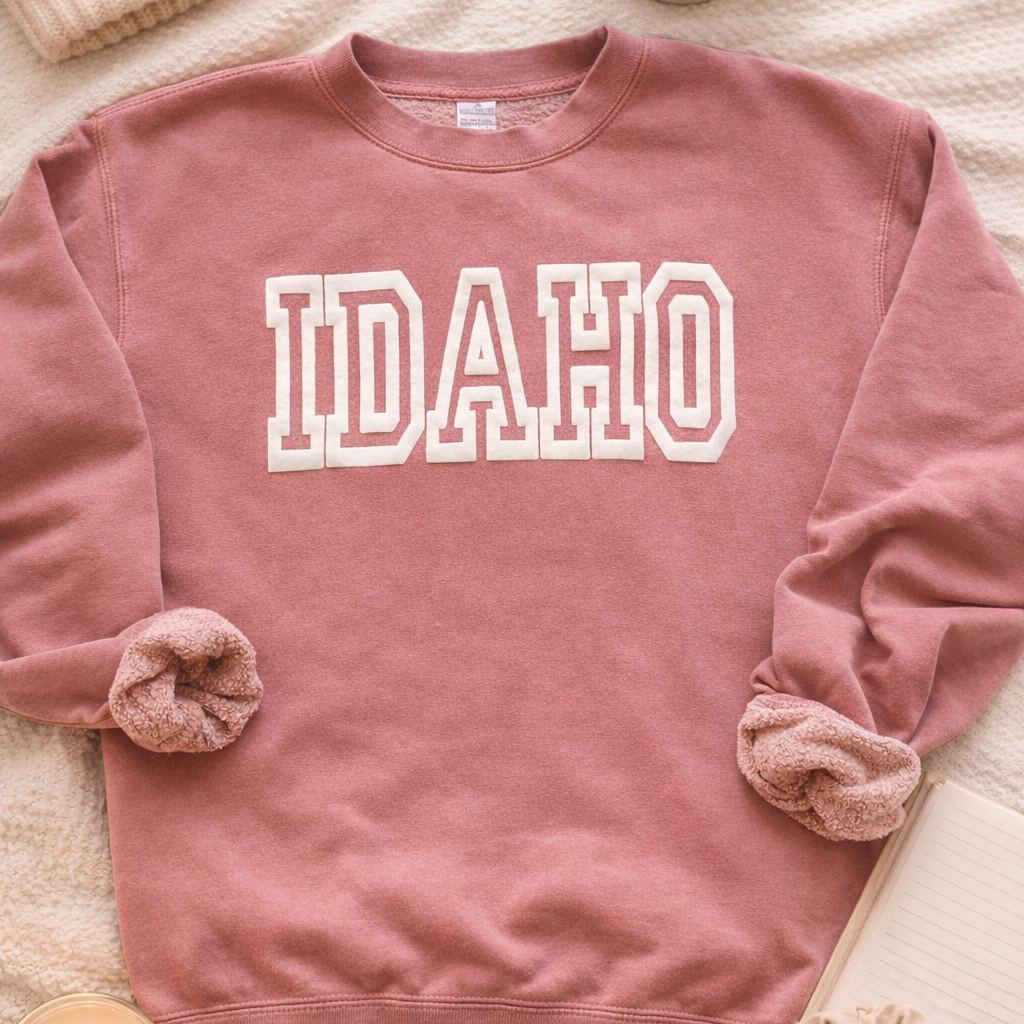 A cute pink Idaho sweater with the word Idaho on it. The Idaho is a puff print.
