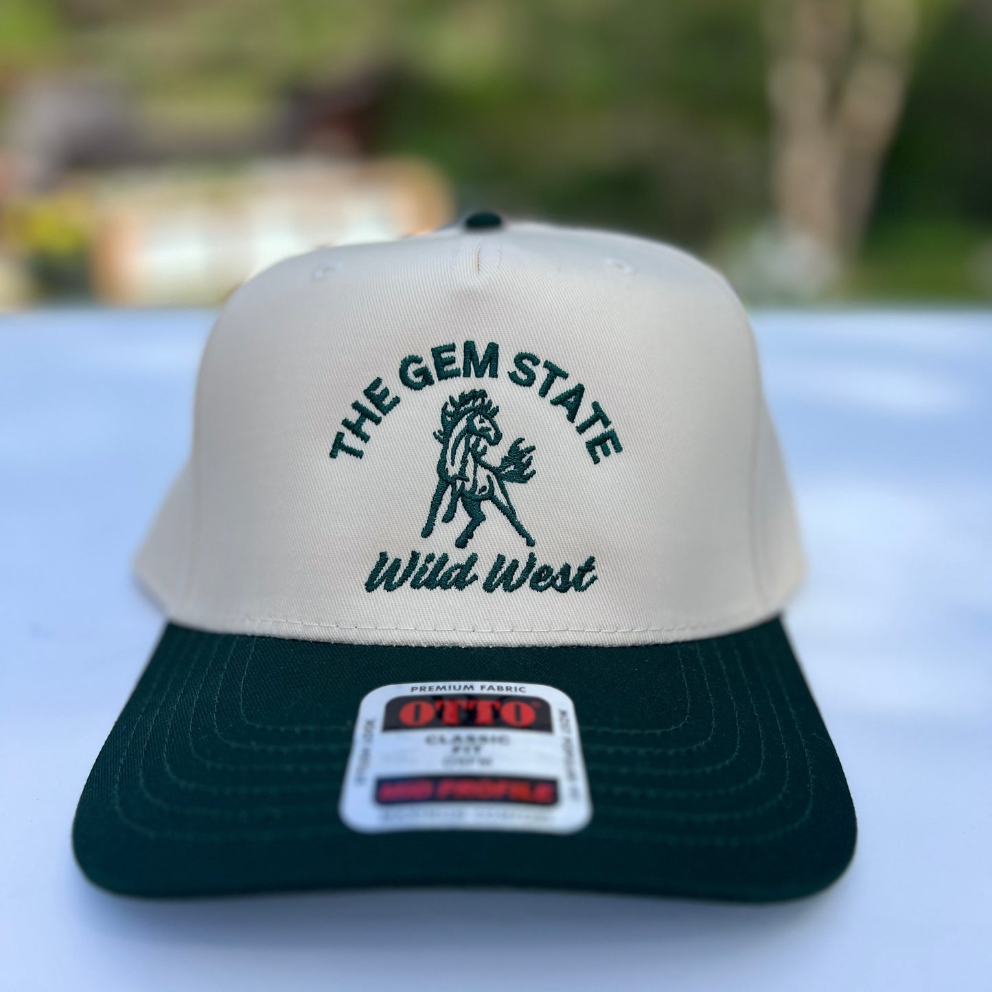 This Idaho Wild West Hat is green and natural colored. This Idaho has has a horse on the front with the words The Gem State, Wild West on it. Designed by TatorJo