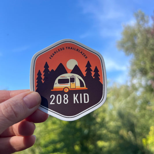 Hexagonal sticker with camping design held against a natural background