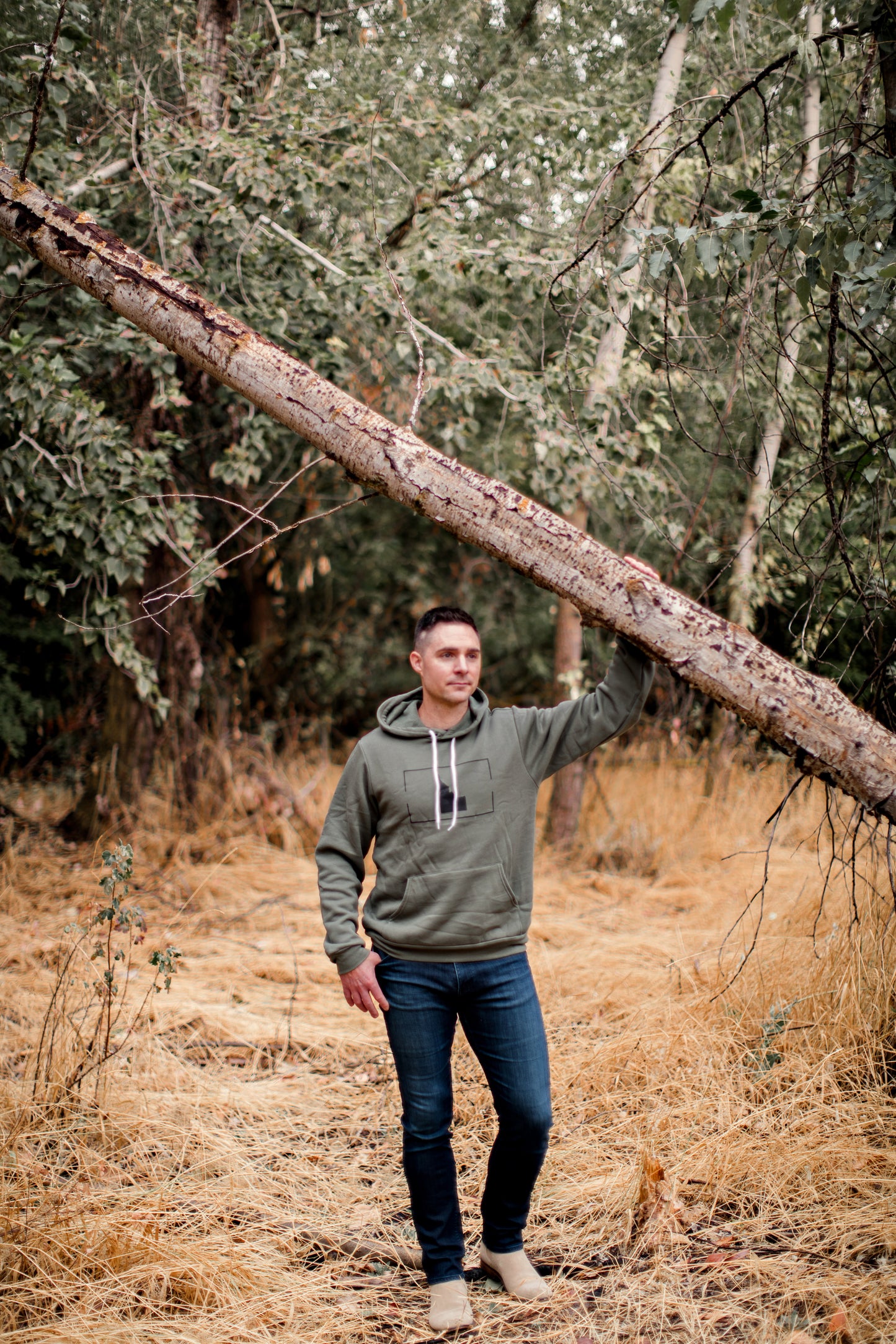 A man in Idaho wearing an Idaho sweatshirt. The man is in green and standing outside in Idaho. The sweatshirt is designed by TatorJo, an Idaho Clothing company