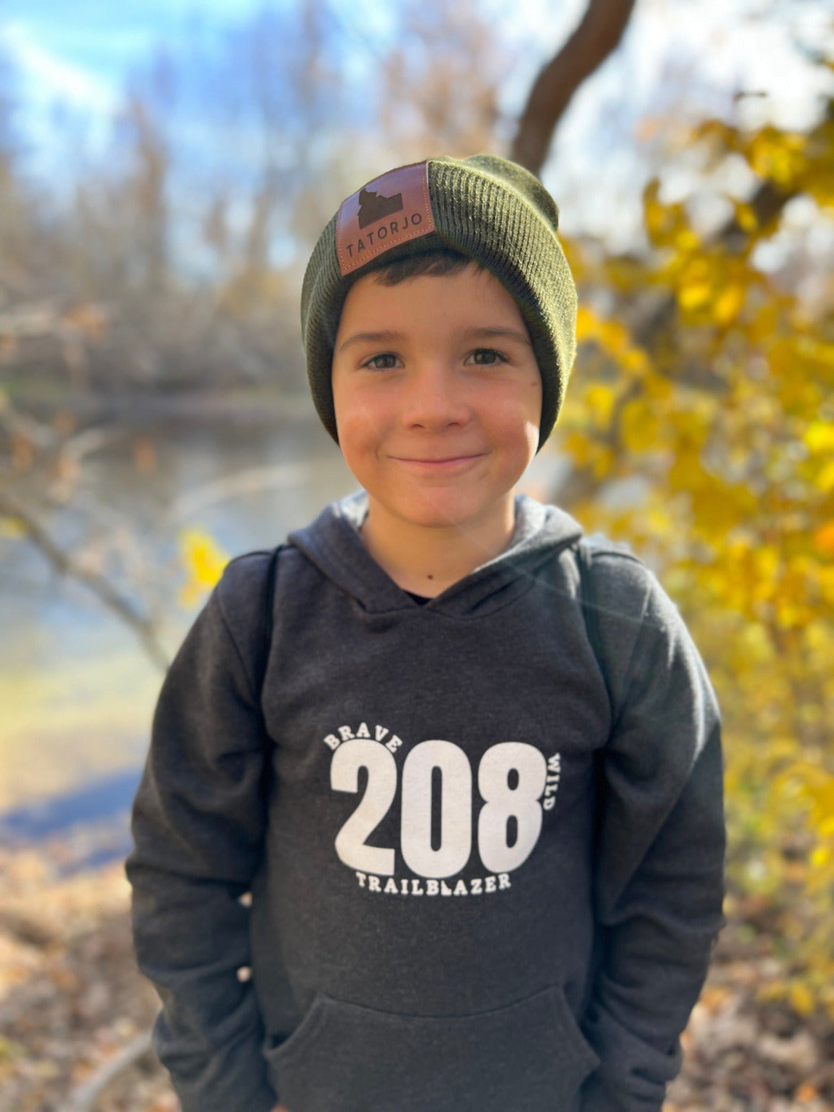 Idaho boy in sweatshirt or hoodie wearing a hoodie that says 208. Idaho apparel is for adventure kids. Idaho Kids are full of adventure. The hoodie stands for Idaho. Idaho clothing is comfy and cozy.'