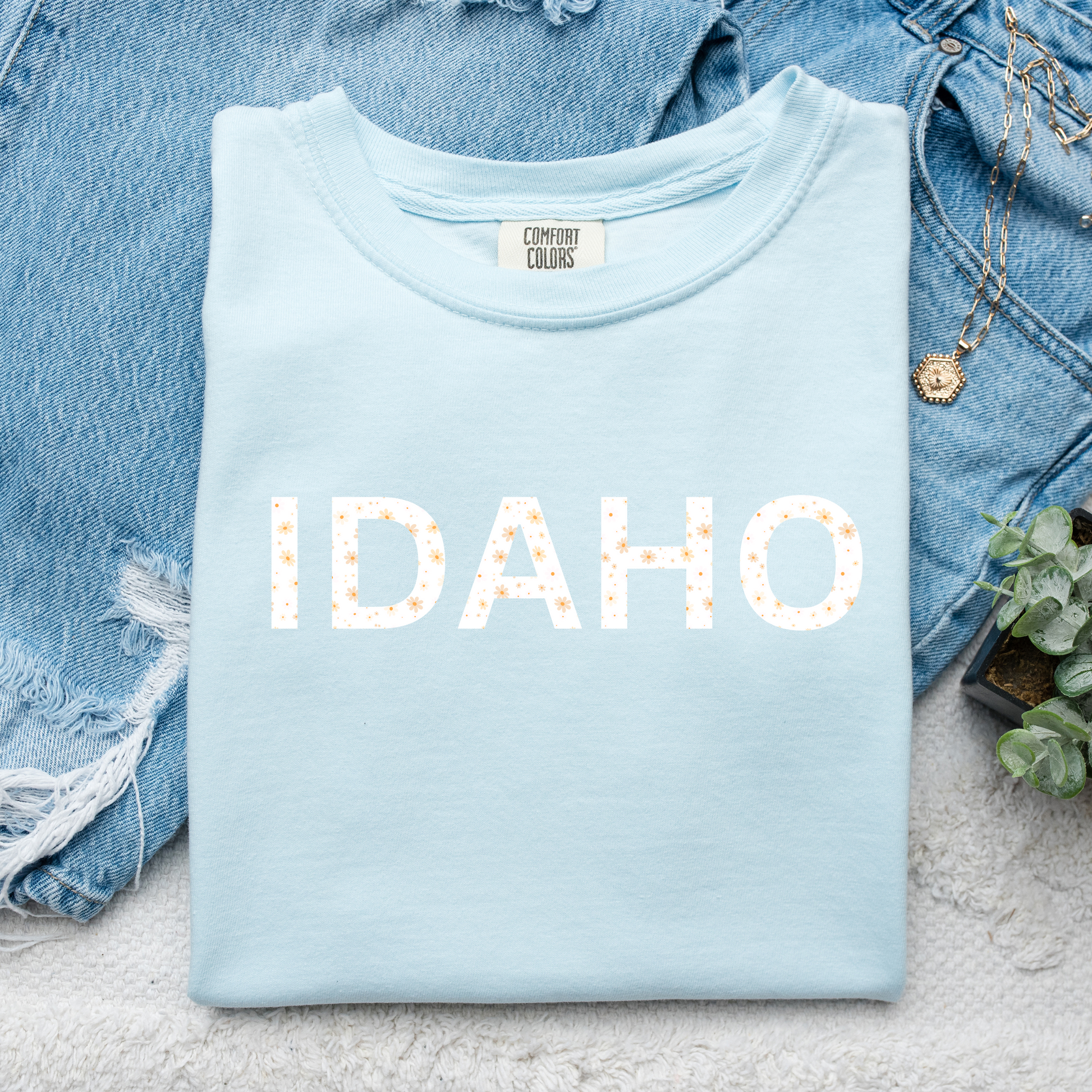 Cute Idaho baby blue t shirt with the word Idaho on it. The word Idaho is in a floral print.