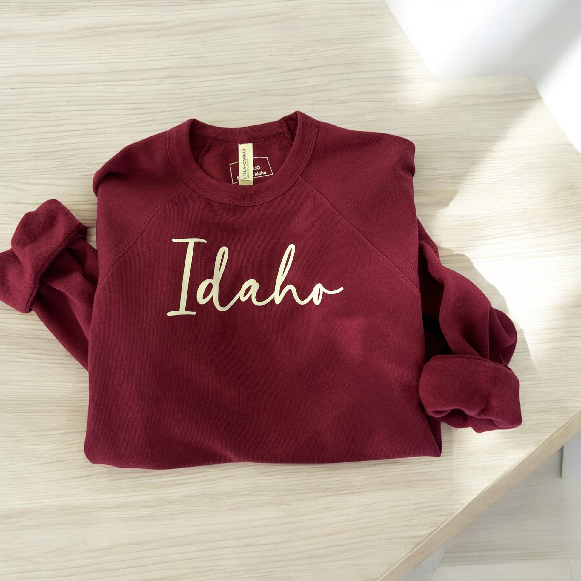 This Idaho Crewneck has Idaho printed on the front in cursive. This sweatshirt is designed by an Idaho Clothing Company that specializes in creating Idaho apparel for Idaho families. This Idaho Brand sweater is maroon and so soft.