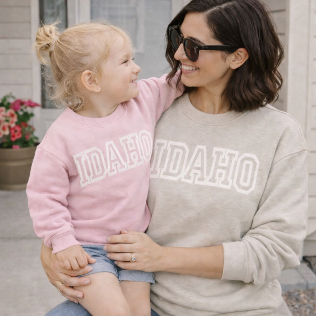 Woman and child wearing Idaho sweatshirts sitting outdoors.