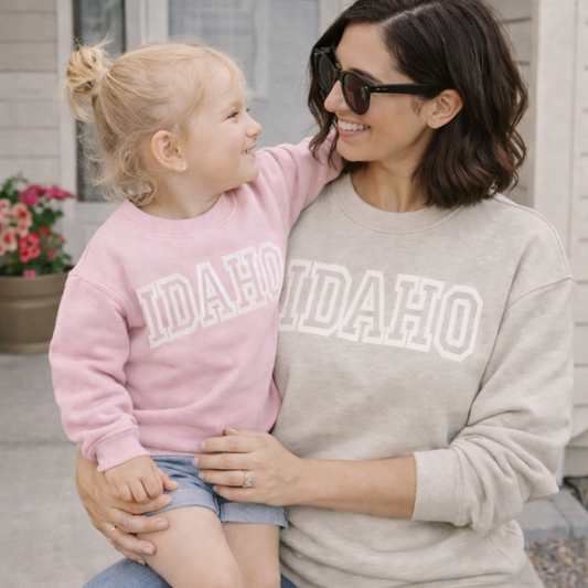 Woman and child wearing Idaho sweatshirts sitting outdoors.
