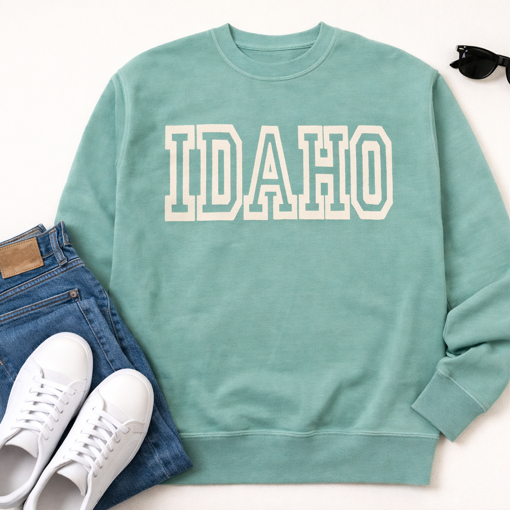 Teal sweatshirt with 'IDAHO' text, paired with jeans and sneakers on a white background