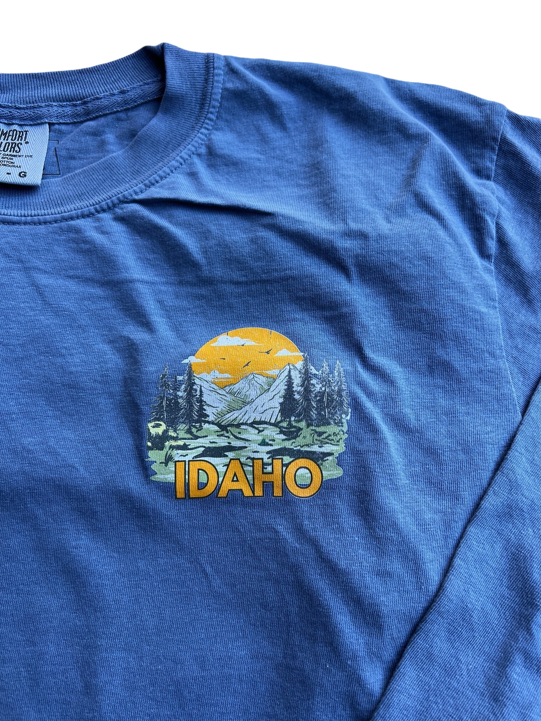 A blue long sleeve shirt that has the word Idaho written on it. The Idaho is a front corner image. This shirt is designed by TatorJo an Idaho Clothing company