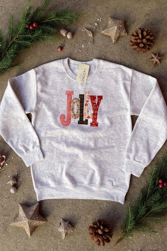White sweatshirt with 'Jolly' design on a textured surface with decorative elements